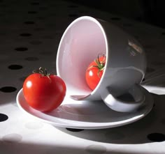 two tomatoes in a white cup on a polka dot tablecloth