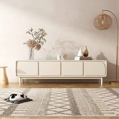 a cat is laying on the floor in front of a white dresser with flowers and vases