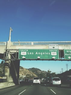 an overpass with two freeway signs above it and cars driving under it on the highway