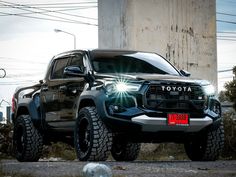 a black toyota truck is parked in front of a concrete structure with power lines above it