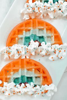 two waffles with white and orange frosting on them sitting next to each other