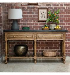 a wooden table with two bowls and fruit on it in front of a brick wall