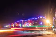 a train is traveling down the tracks at night with lights on it's side