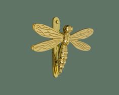 a gold brooch with a dragonfly on it's back and two smaller wings