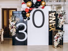 balloons and flowers decorate the entrance to an elegant 30th birthday party in white, black, and gold