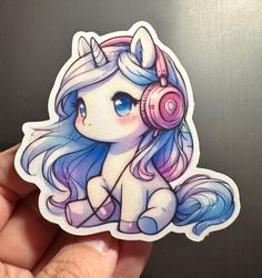 a hand holding a sticker with an image of a unicorn wearing headphones and listening to music