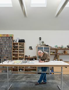 a man standing at a table in a room with lots of books