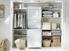 a white washer and dryer sitting inside of a closet next to a laundry basket