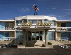 a person on top of a pole in front of a hotel