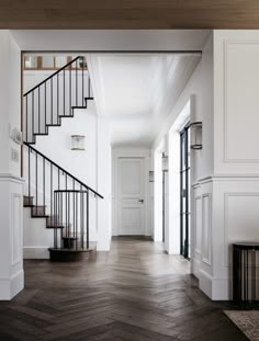 an empty hallway with wooden floors and white walls