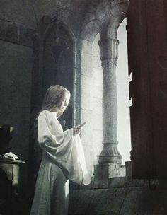 a painting of a woman standing in front of a window looking at her cell phone