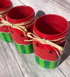 three watermelon jars tied with twine on top of a wooden table next to each other