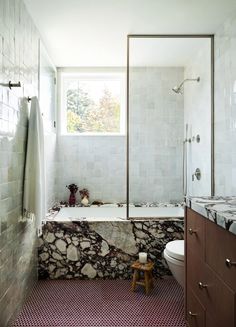 a bath room with a toilet a sink and a bath tub next to a window