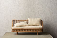 a wooden couch sitting on top of a cement floor next to a white and beige wall