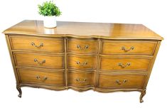 a wooden dresser with many drawers and a potted plant on it's top