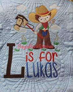 a child's quilt with the letter l on it and a horse in the background