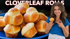 a woman standing in front of a pile of bread rolls