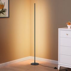 the floor lamp is next to a white dresser