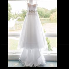 a wedding dress hanging in front of a window