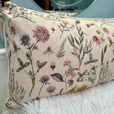 a pillow with flowers on it sitting on a white furnishing next to a mirror