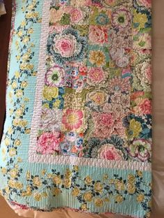 an old quilt is laying on top of a bed with the cover pulled down to show it's colorful flowers