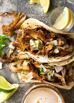 three tacos with meat, onions and cilantro next to a glass of beer