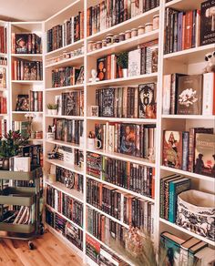 a bookshelf filled with lots of books on top of white shelves next to a wooden floor