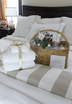 a wicker basket on top of a bed with white sheets and pillows next to it