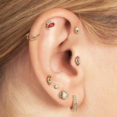 a close up of a person wearing ear piercings with different colored stones on them