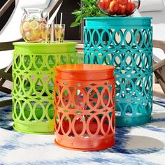 three colorful plastic containers sitting on top of a blue and white rug next to chairs