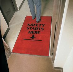 a red door mat with the words safety starts here and an arrow pointing up on it