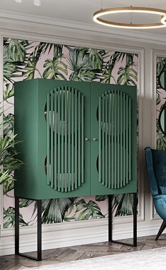 a green cabinet next to a blue chair in front of a wall with palm leaves on it