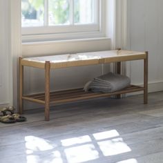 a wooden bench sitting in front of a window next to a pair of slippers