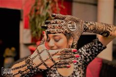 a woman holding her hands up to her face with hendi tattoos on it's arms