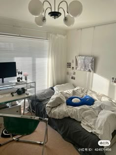 an unmade bed sitting next to a desk and computer monitor on top of it