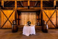 the table is set up in front of two wooden barrels and lights are hanging from the ceiling