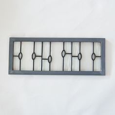 an iron and glass window frame hanging on the wall with white walls in the background