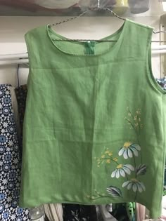 a green top with white flowers on it hanging from a clothes rack in a closet