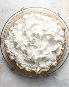 a pie sitting on top of a wire rack covered in whipped cream and icing