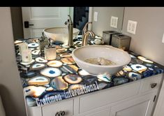 a bathroom sink sitting under a mirror next to a counter top with a bowl on it