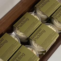 six jars of pudding sitting on top of a wooden box with labels in them that say, almond pudding pudding