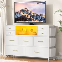 a flat screen tv sitting on top of a white dresser