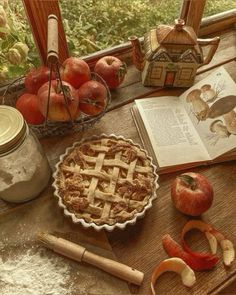 an apple pie sitting on top of a wooden table next to apples and other fruit