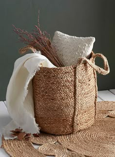 a basket with two white pillows and some brown leaves on the floor next to it