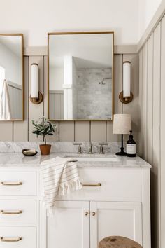 a bathroom vanity with two mirrors above it and a stool in front of the sink