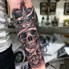 a skull with a crown tattoo on its arm is shown in black and grey colors