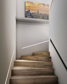 there is a staircase with wooden steps leading up to the top floor and cityscape in the background