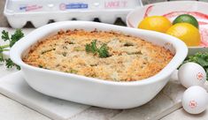 a casserole dish is shown with lemons and parsley in the background