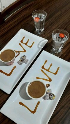 two white plates topped with desserts on top of a wooden table next to glasses