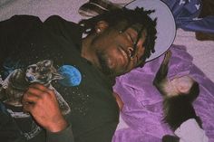 a man laying on top of a bed next to two kittens and wearing a hat